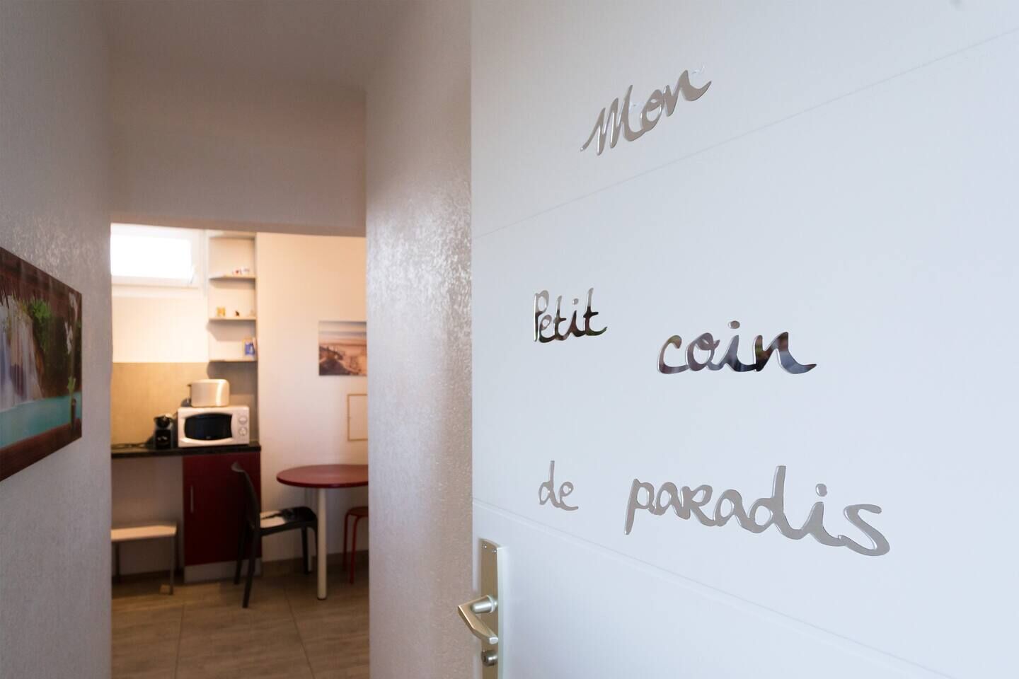 Un pasillo con una zona de cocina, una mesa de comedor y una puerta con texto parcialmente visible.