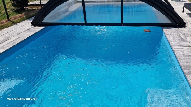 Piscina con cubierta de seguridad, rodeada de un solárium con baldosas.