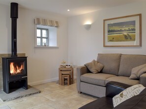 A cozy living room with a fireplace, a sofa, a small table with a tray of snacks, and a framed painting on the wall.