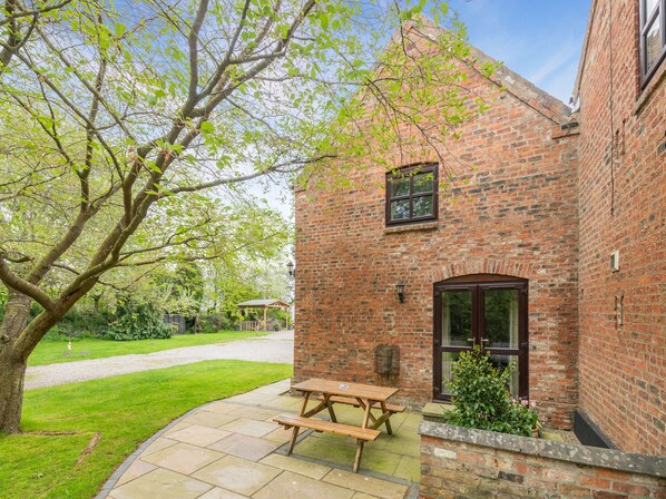 A brick building with a wooden bench and a small garden area. - 3 bedroom accommodation in York (York)