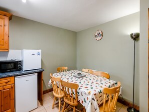 A compact kitchen with a microwave, a small refrigerator, wooden chairs, and a table with a patterned tablecloth. - 3 bedroom accommodation in York (York)