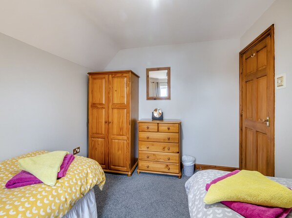 A bedroom with two beds, a wooden wardrobe, a dresser, and a mirror on the wall. - 3 bedroom accommodation in York (York)