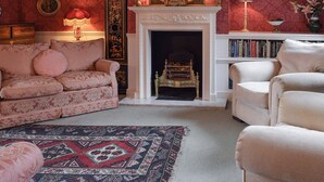 A traditional living room with a fireplace, a sofa, armchairs, and a patterned rug.