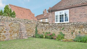 A stone wall with a brick house, a grassy yard, and a clear sky. - 2 bedroom accommodation in Heacham, near King&rsquo;s Lynn (Heacham, near King&rsquo;s Lynn)