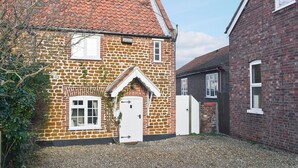 A traditional stone house with a tiled roof, a white door, and a small garden area with gravel. - 2 bedroom accommodation in Heacham, near King&rsquo;s Lynn (Heacham, near King&rsquo;s Lynn)