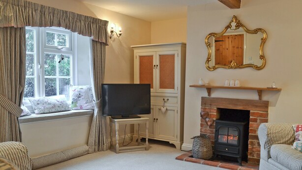 A cozy living room with a fireplace, a television on a stand, and striped upholstered furniture. - 2 bedroom accommodation in Heacham, near King&rsquo;s Lynn (Heacham, near King&rsquo;s Lynn)