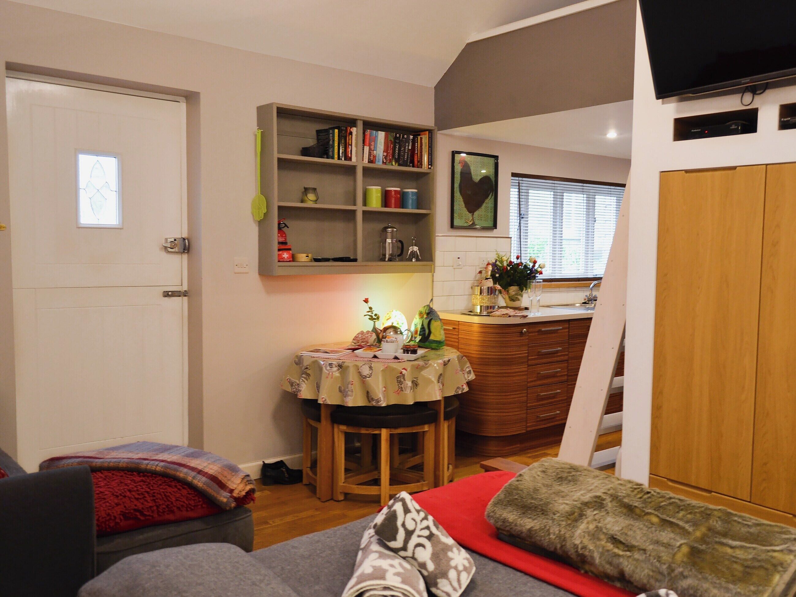 Un espacio habitable compacto con comedor, estantería y televisor.