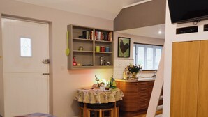 Un espace de vie compact comprenant un coin repas, une bibliothèque et un téléviseur.