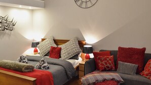 Une chambre confortable avec un lit, deux canapés, un banc en bois et une horloge murale.