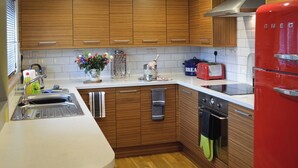 Une cuisine moderne avec des meubles en bois, un réfrigérateur rouge, un four encastré et un évier.