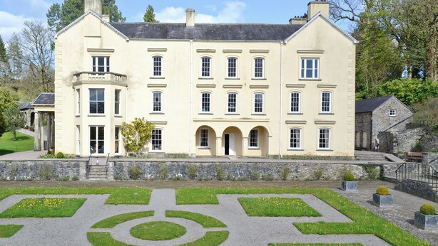 A large, cream-colored building with multiple windows and a symmetrical facade.
