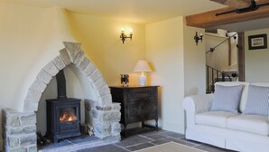 Una sala de estar acogedora con chimenea de piedra, un sofá blanco y una lámpara.