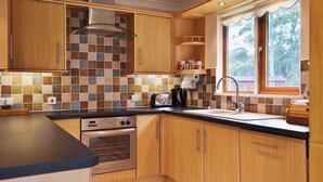 Una cocina moderna con armarios de madera, salpicadero de azulejos y un ventanal que ofrece luz natural.