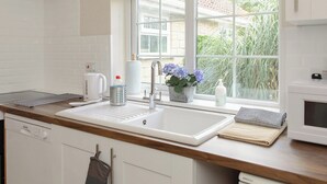 A modern kitchen with a white sink, stainless steel faucet, and a window with a view of greenery.