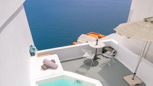 Un espace piscine aménagé sur le toit, offrant une vue sur la mer, avec des murs blancs et une petite table accompagnée d’une chaise.