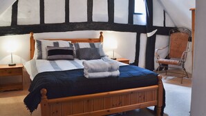 A bedroom with a wooden bed, two bedside tables with lamps, a chair, and exposed black and white beams on the ceiling. - 4 bedroom accommodation in York (York)