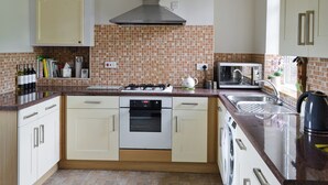 A compact kitchen with a gas stove, oven, microwave, and a sink.