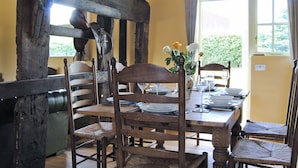 Un comedor con una mesa y sillas de madera, un jarrón con flores y una ventana con cortinas.