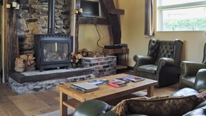 Una sala de estar acogedora con chimenea de piedra, una mesa de centro de madera con libros y sillones de cuero.