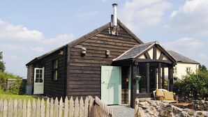 Una casa de madera con chimenea, un muro de piedra y una valla de madera.