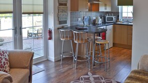 Een moderne keuken met een bar, houten kastjes en een brandblusser.
