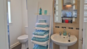 Een badkamer met een toilet, een wastafel en een handdoekrek met opgevouwen handdoeken.
