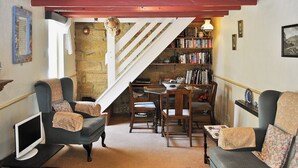 Un salon chaleureux avec un escalier, une bibliothèque et un coin repas.