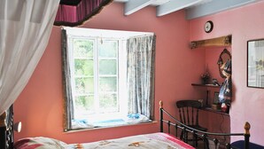 Une chambre à coucher avec un lit, une chaise, une fenêtre avec des rideaux, une horloge et une étagère avec des objets.