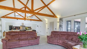 A spacious living area with two brown sofas, a wooden coffee table, and a kitchen in the background. - 3 bedroom accommodation in Wicken, near Ely (Wicken, near Ely)