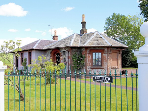 Una casa de ladrillo con techo a dos aguas, una chimenea y un cartel que indica 'CONHEATH PRIVATE ROAD'.