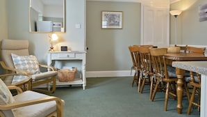 A cozy dining area with wooden chairs and a table, a white console table with a lamp, and a large mirror on the wall. - Ideal family accommodation enjoying fine mountian views from most rooms. (Keswick)