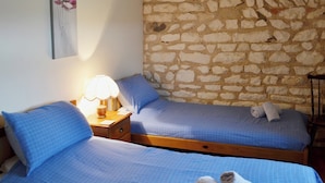 Ein Schlafzimmer mit zwei Betten, einer Steinwand und einem Blumenbild.