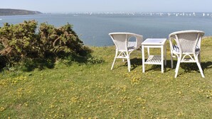 A grassy area with two wicker chairs and a small table, overlooking a body of water with sailboats. - 2 bedroom accommodation in Freshwater (Freshwater)