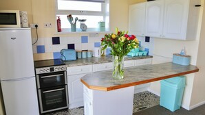 A compact kitchen with a central island, a microwave, a toaster, and a sink. - 2 bedroom accommodation in Freshwater (Freshwater)