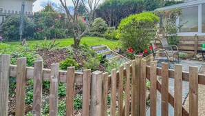 A garden with a wooden fence, a tree, and a bench.