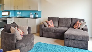 A compact living space with a kitchenette, a sofa set, and a blue rug. - 2 bedroom accommodation in Porthmadog (Porthmadog)