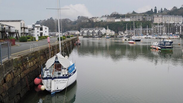 A harbor with boats docked, a stone wall, and buildings in the background. - 2 bedroom accommodation in Porthmadog (Porthmadog)