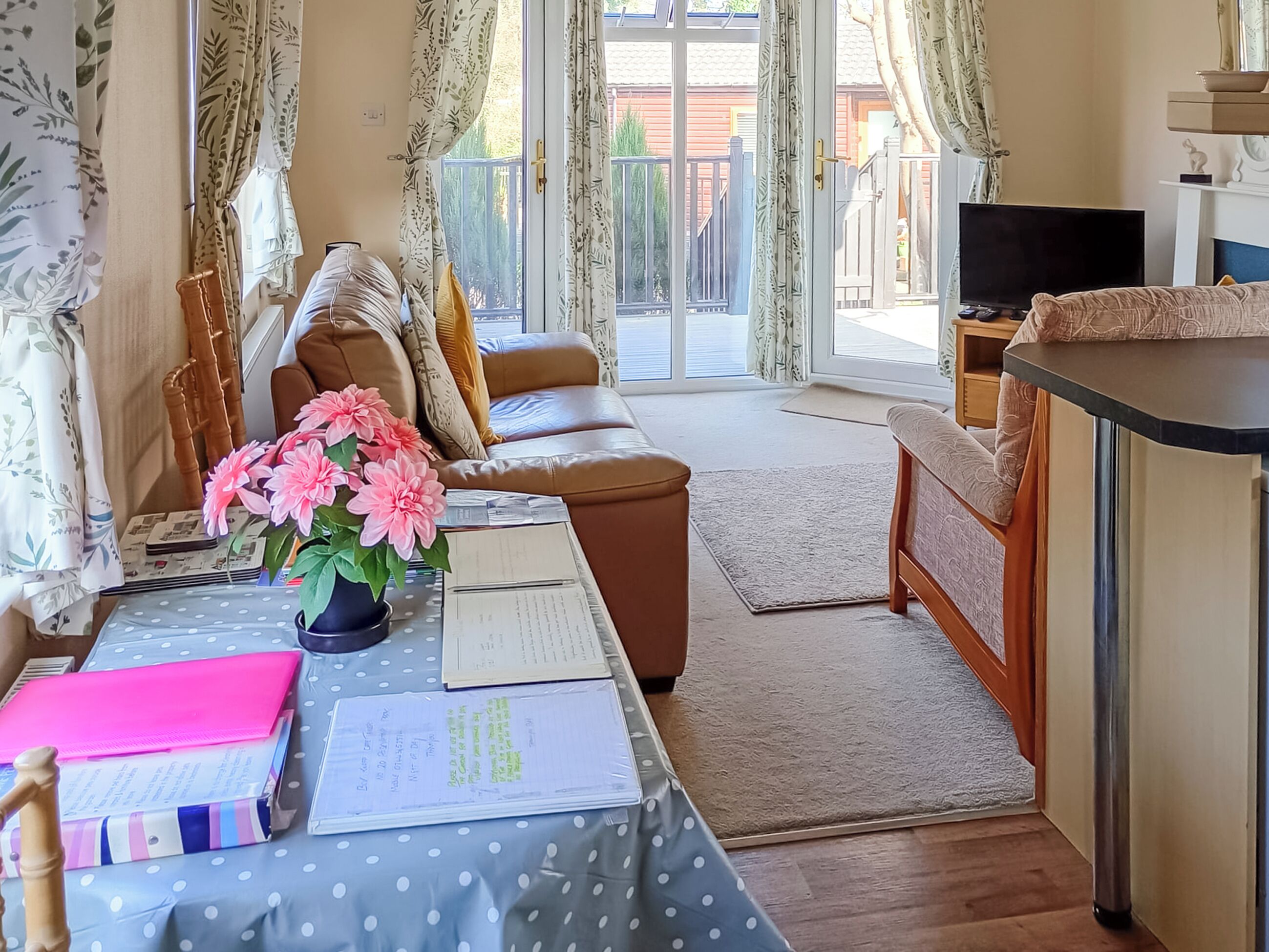 A room with a sofa, a table with a vase of flowers, a television, and a window with curtains.