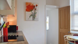 A modern kitchen with a wooden countertop, a painting of flowers, and a door leading to another room. - 1 bedroom accommodation in Filey (Filey)
