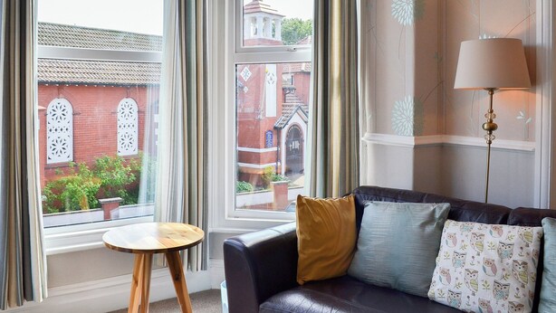 A room with a leather sofa, a small wooden table, and a lamp. - 1 bedroom accommodation in Filey (Filey)