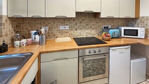 Une cuisine de taille réduite, équipée d’un évier, d’une cuisinière, d’un four à micro-ondes et d’un petit réfrigérateur.