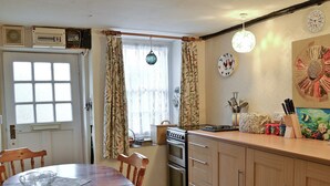 A kitchen with wooden cabinets, a stove, and a dining table with chairs. - 3 bedroom accommodation in Lympstone, near Exmouth (Lympstone, near Exmouth)