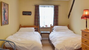 A room with two single beds, a wooden dresser, a chair, a window with plaid curtains, and a wall-mounted picture. - 3 bedroom accommodation in Lympstone, near Exmouth (Lympstone, near Exmouth)