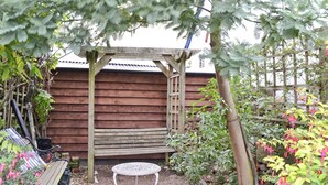 A wooden pergola with a table underneath, surrounded by various plants and a wooden fence. - 3 bedroom accommodation in Lympstone, near Exmouth (Lympstone, near Exmouth)