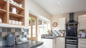 A modern kitchen with white cabinets, a Bosch dishwasher, a black range hood, and a tiled backsplash. - 3 bedroom accommodation in Bleadon, near Weston-super-Mare (Bleadon, near Weston-super-Mare)