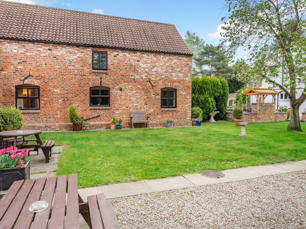 A brick building with a tiled roof, a wooden bench, and a picnic table.