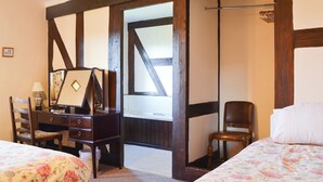 Ein Schlafzimmer mit Bett, Sessel, Schminktisch und Spiegel.