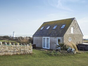 Une maison en pierre avec un toit en pente, une seule porte et un petit porche.