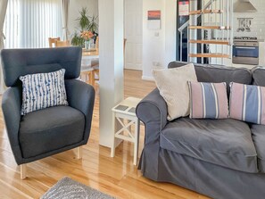 Un salon moderne avec un canapé gris, un fauteuil foncé et une petite table blanche.