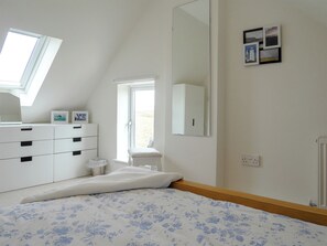 Une chambre à coucher avec un lit, une commode, un miroir et une fenêtre.